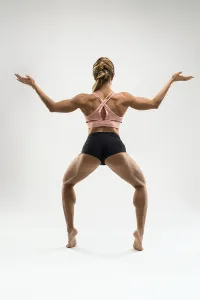 Full body back view of unrecognizable barefoot female athlete with strong muscular body dressed in sport bra and shorts