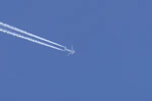 Boeing 737 jet passenger aircraft of Norweign Air with a vapour trial or contrail behind flying in a blue sky
