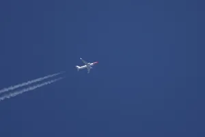 Boeing 737 jet passenger aircraft of Norweign Air with a vapour trial or contrail behind flying in a blue sky