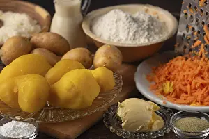 Boiled potatoes and grated carrots next to flour
