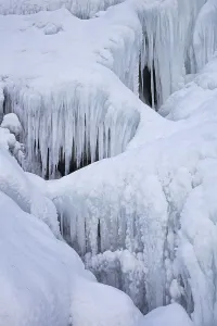 Bora del Nivolet, ice formations and icicles on waterfall of frozen river in winter