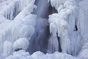 Bora del Nivolet, ice formations and icicles on waterfall of frozen river in winter