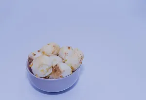 A bowl of bread rolls set against a simple white background with a blue tint