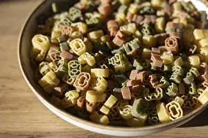 A bowl filled with multi-colored number shaped pasta featuring various digits