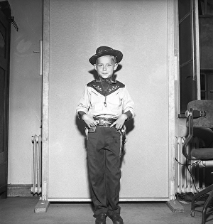 Boy in the 1950s. A boy is dressed in cowboy clothes, shirt, gun holster and cowboy hat and holds two toy revolvers. 1950. Kristoffersson ref AZ47-9