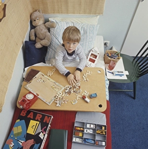 A boy in bed in the 1960s. He probably has a cold and needs to stay home