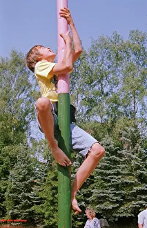 Boy climbs on maypole, barefoot