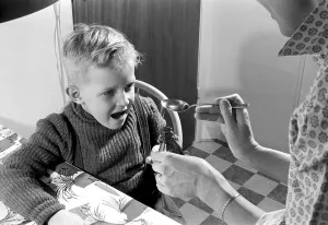 A boy is sick and won't take his medicine. His mother holds out a spoon and waits for him to gape and take it, and he does. He opens his mouth and takes it even though it for sure does not tase so good. Sweden 1956