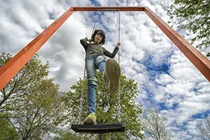 A boy stands on a swing. View from below