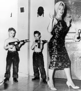 Two boys with rifles against mother, ca