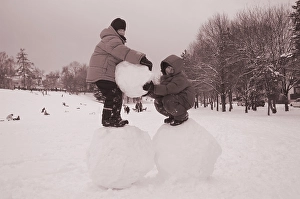 Two boys standing on big snoww balls