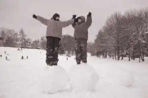 Two boys standing on big snoww balls