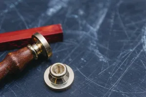 Brass seal with red wax on a textured dark background