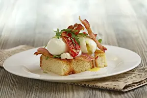 Breakfast of soft-boiled egg, bacon and tomato on wooden table