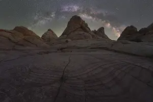 A breathtaking night sky view featuring the Milky Way over textured rock formations in the Utah desert