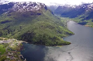 Breathtaking panorama of a fjord with snow-capped mountains and dense forests