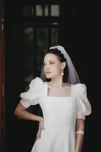 A bride in a vintage-style white dress with puffed sleeves