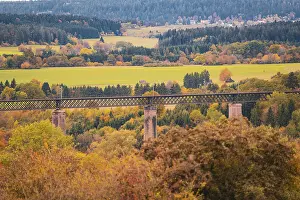 Bridge over an autumn landscape with colorful trees and meadows