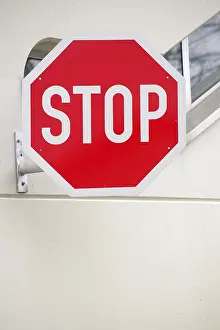A brightly coloured stop sign on the facade of a building<br> A brightly coloured stop sign on the fa