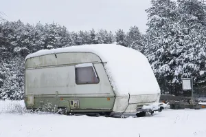 Broken tourist car trailer covered with snow in the winter forest landscape