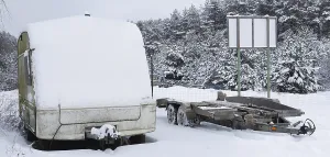 Broken tourist car trailer covered with snow in the winter forest landscape