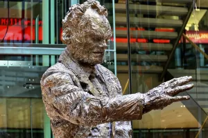Bronze statue of a man in a modern lobby of a building