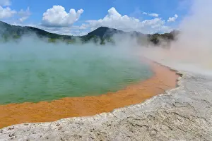 Bubbling mineral spring with steam and surrounded by mountains