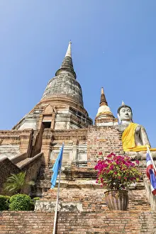 Buddha statue at the bottom of a large ancient pagoda on blue sky background at Wat Yai Chai Mongkon temple in Phra
