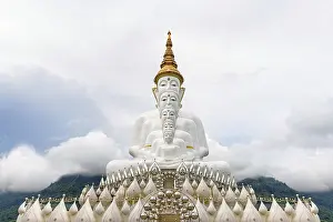 Buddha statue has large white five body on mountain surrounded by nature with cloud fog cover at Wat Phra That Pha Sorn