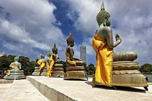 Buddha statues on the water with yellow robes against an urban backdrop
