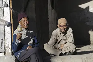 Buddhist Ladakhis with prayer wheel in front of a shop in Leh