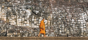 Category Buddhism Prints: Buddhist monk walks in front of old stone wall