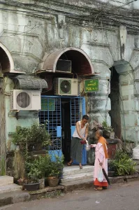 Buddhist nun receiving a rice donation outside a shop