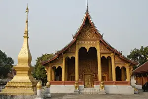 Buddhist Temple in gold and dark red next to a small gold stupa