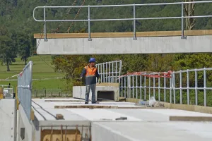 Builders construct a concrete bridge over a small river in Westland