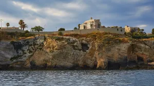 Building on a cliff under a cloudy sky next to the sea