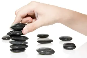 Building a Zen garden. hand and stones on white background