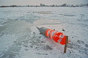 Buoy lying on ice rink, frozen Elbe