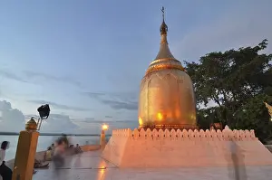 Burmese visitors and pilgrims at the gilded Bupaya Pagoda at the Ayeyarwady river in the evening light