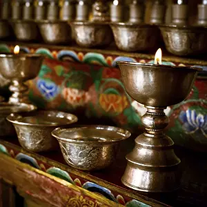 Burning oil lamps and offering bowls at Buddhist monastery temple