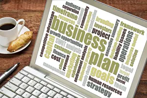 Business plan word cloud on laptop with cup of coffee