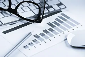 Business workplace with keyboard glasses and financial documents on table