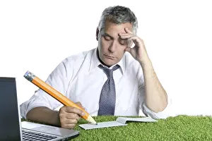 Businessman senior sign bank check pensively humor gesture big pencil green grass desk