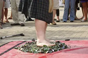 Busker standing barefoot on broken glass bottles