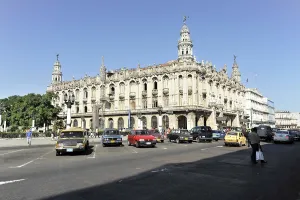 Busy street scene with historic building and vintage cars in the city by daylight