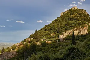 Byzantine Castle of Mystras, Ancient ruins spread on a green hill under a clear blue sky