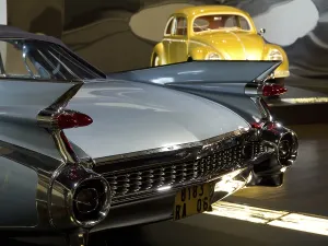 Cadillac with fins and yellow VW Beetle in the background in an exhibition