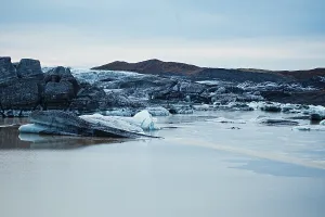 Calm, icy landscape with rocks and a blue sky