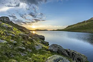 Calm lake with mountains and rocks at sunrise