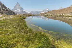 A calm lake reflects a high mountain